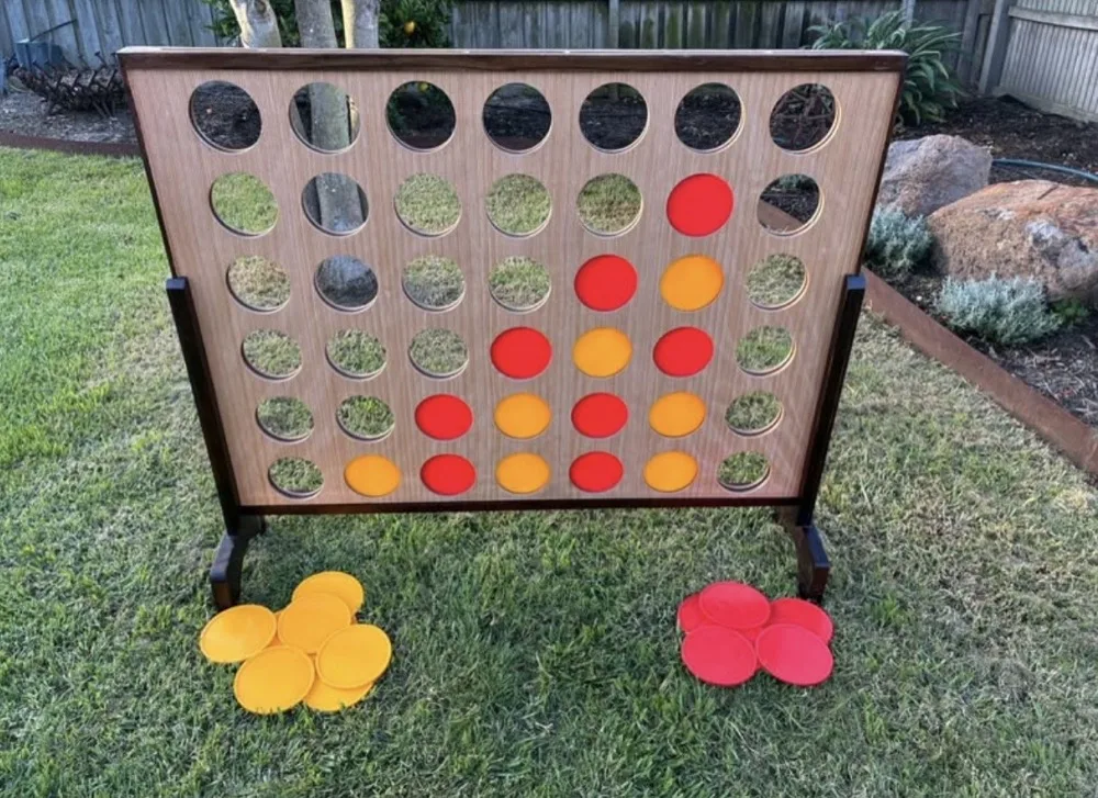 Giant wooden Connect Four set up on a backyard lawn
